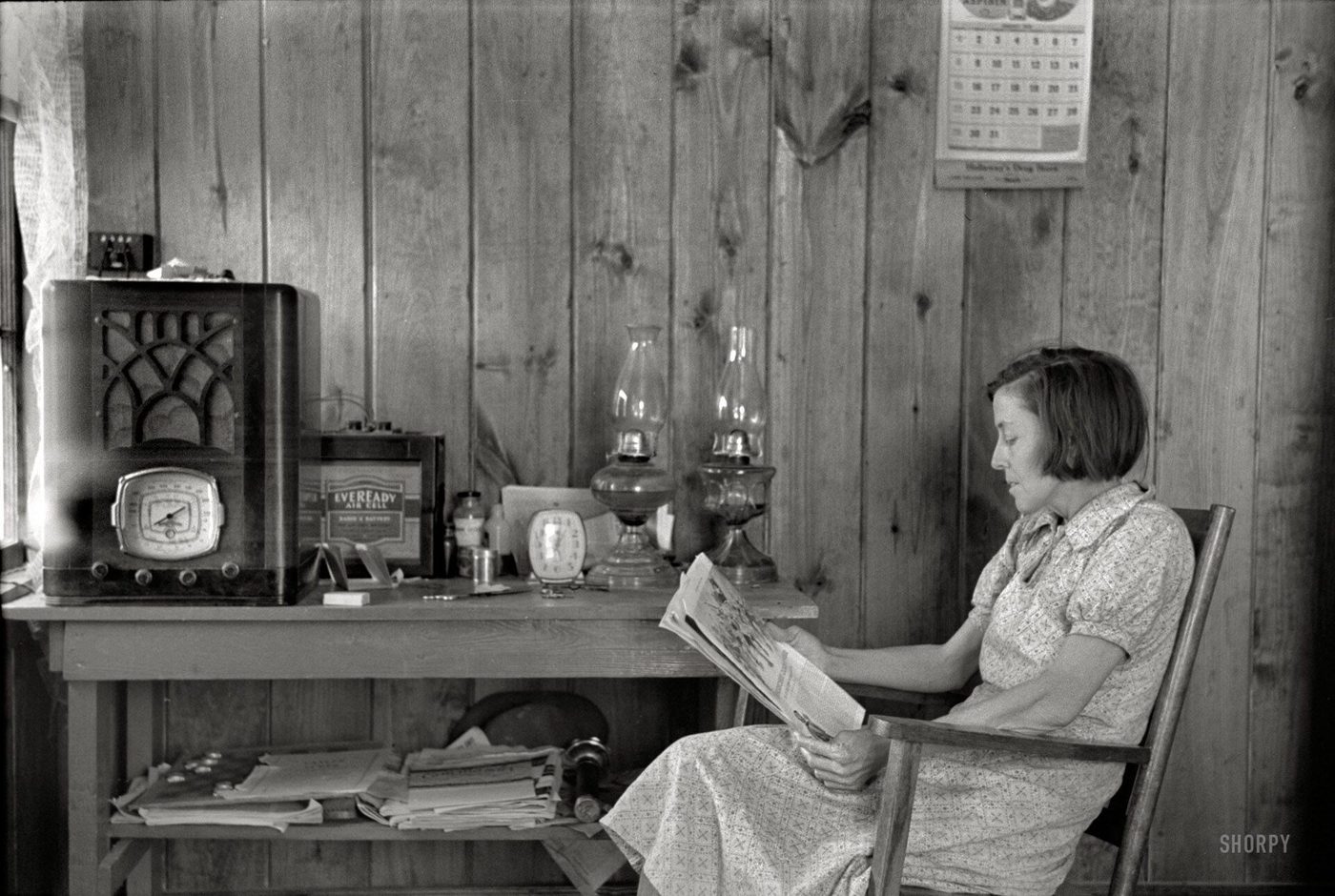 Black and white photograph of a woman reading at a desk