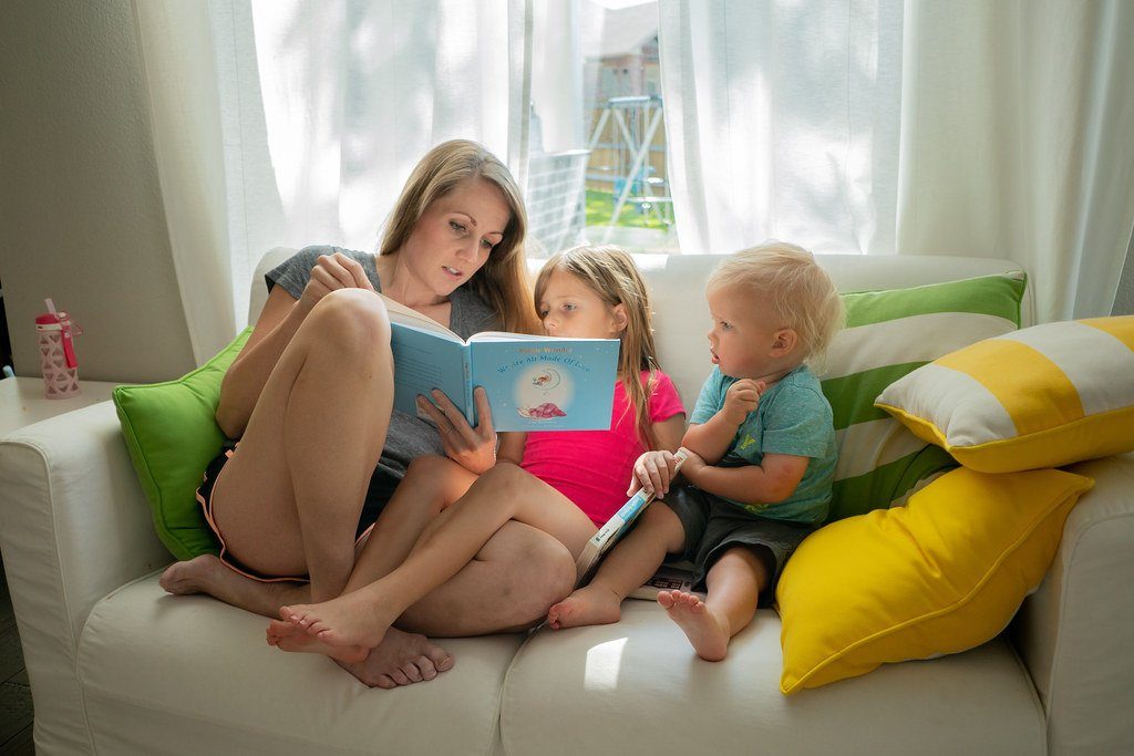 A mother reading a picture book with two young children