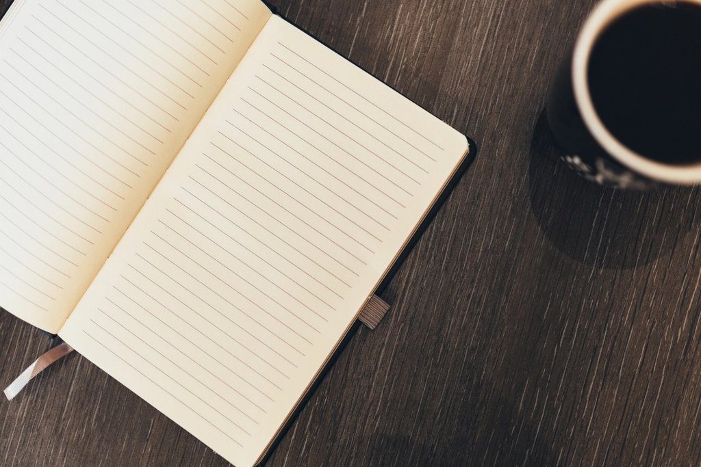 Open notebook and coffee on a dark desk