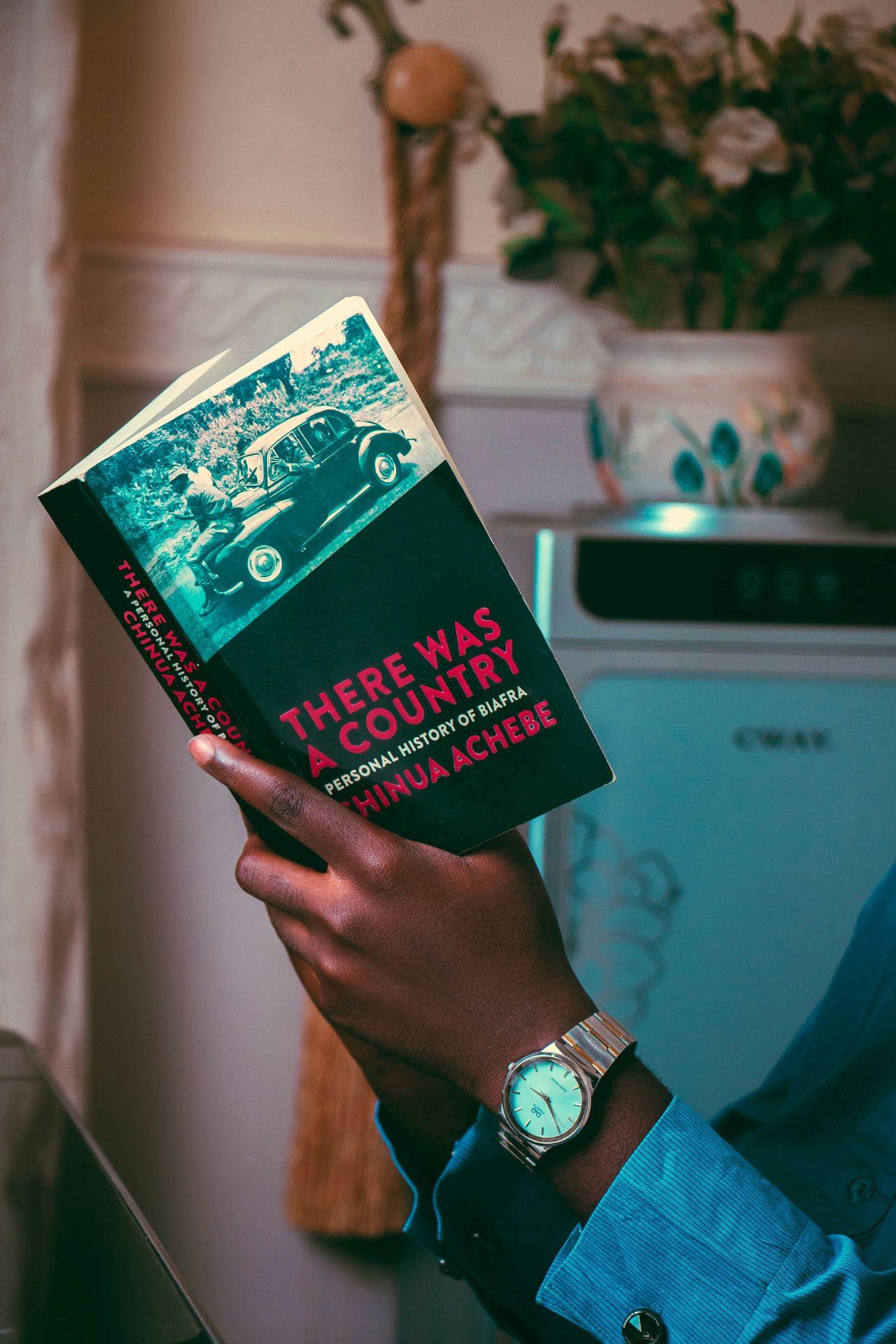 Hand holding a paperback while reading indoors
