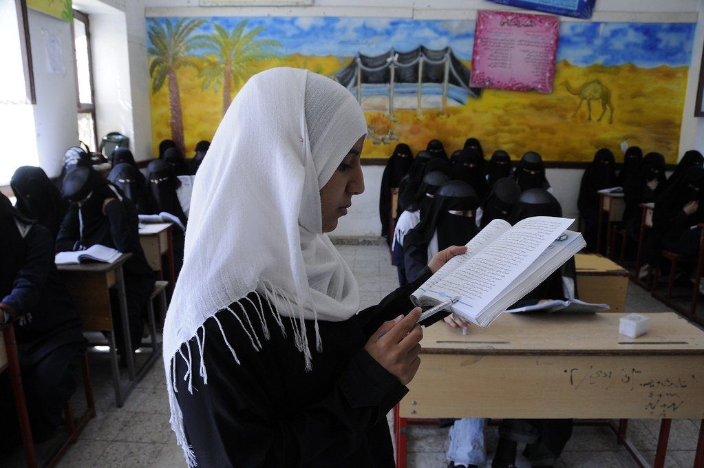 A young student reading a book in a classroom