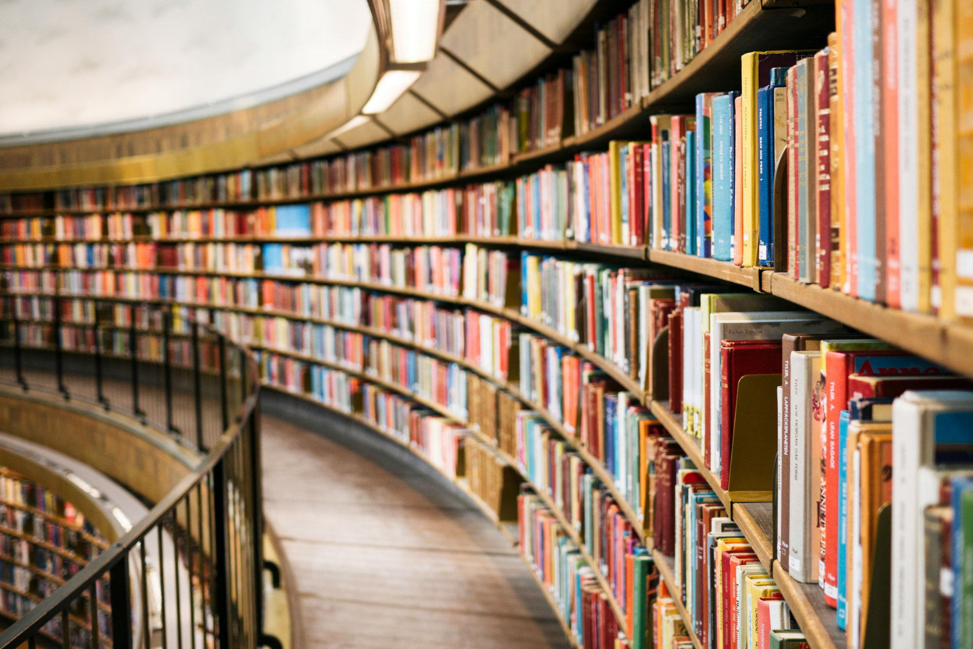 Curved shelves packed with books in a public library reading room