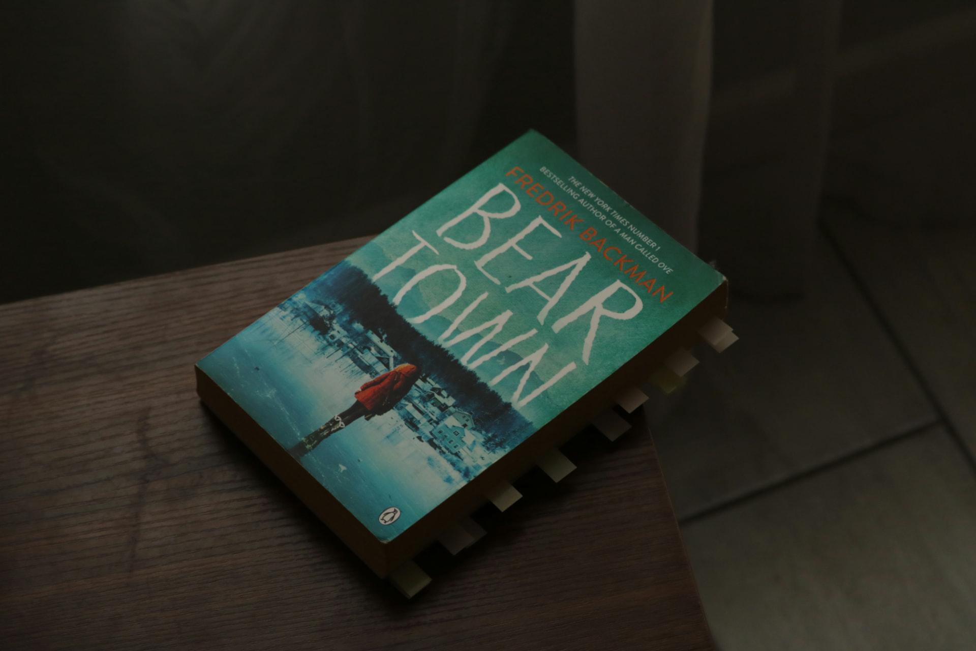 Bookmarked paperback resting on a wooden table